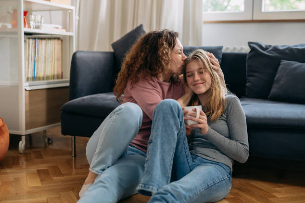 mother kiss her daughter while sitting on floor in living room mother kiss her daughter while sitting on floor in living room